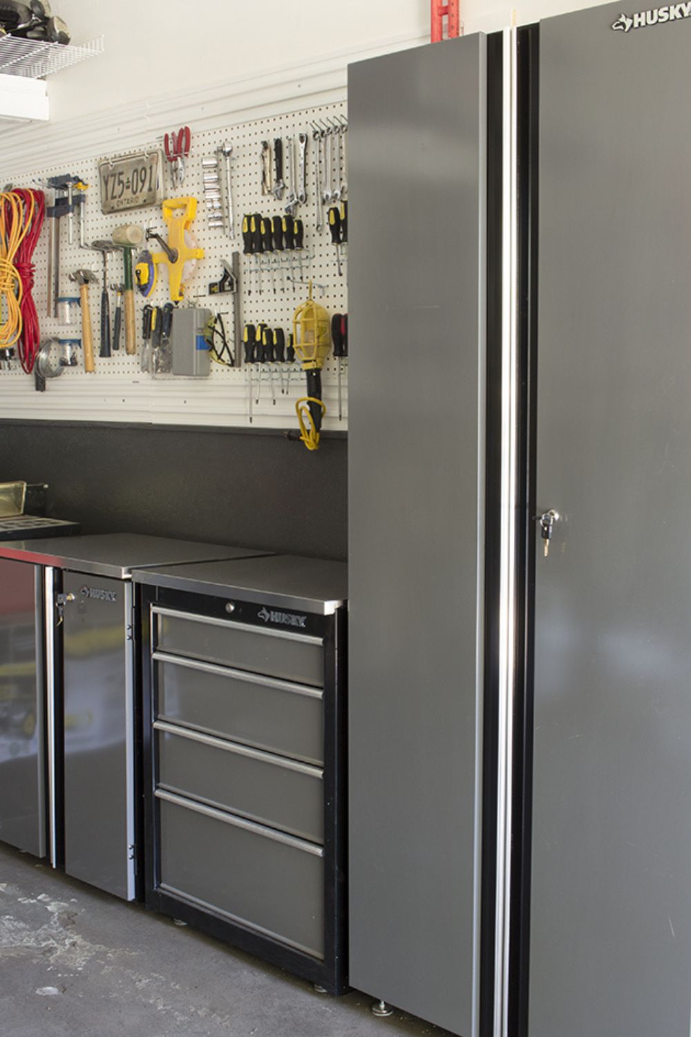 Two lines of tools hung on a peg board next to a large metal cabinet in a garage. The link leads to "Garage Organization Ideas" on HomeMadeLovely.com.