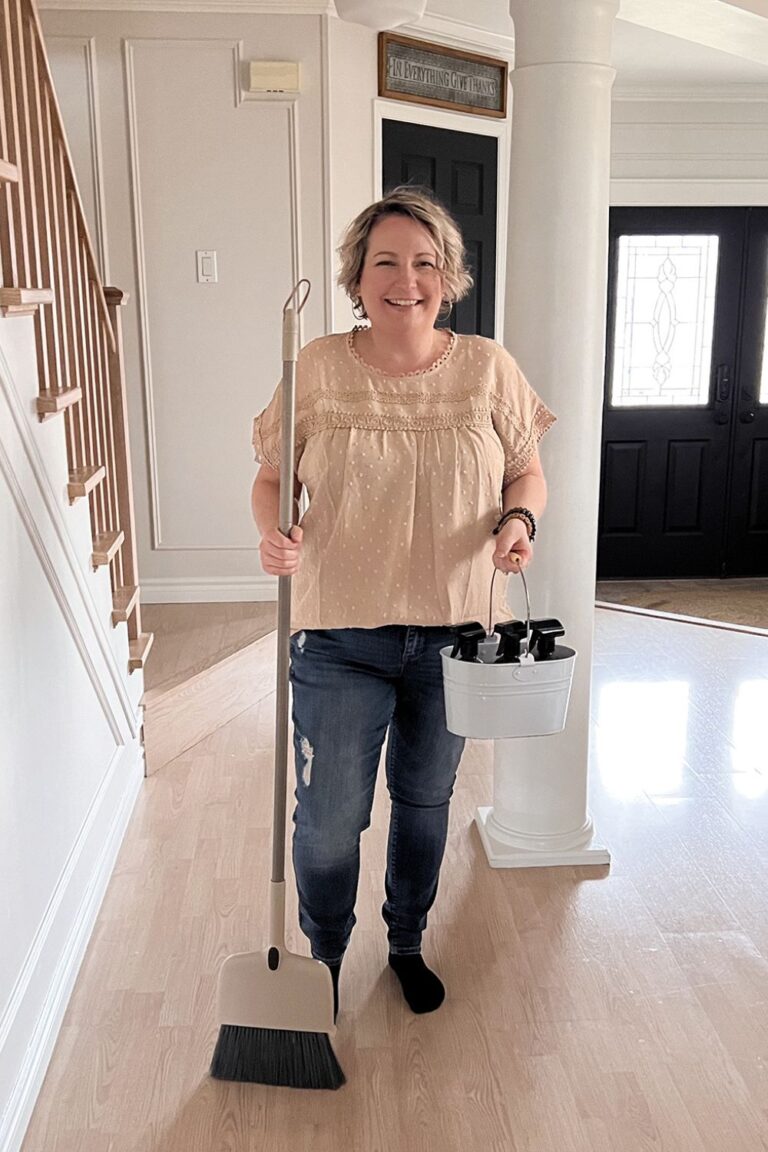 Shannon standing in the hallway with a bucket of cleaning supplies in her hand. The link leads to "7 day spring cleaning challenge for your cluttered home" on HomeMadeLovely.com.