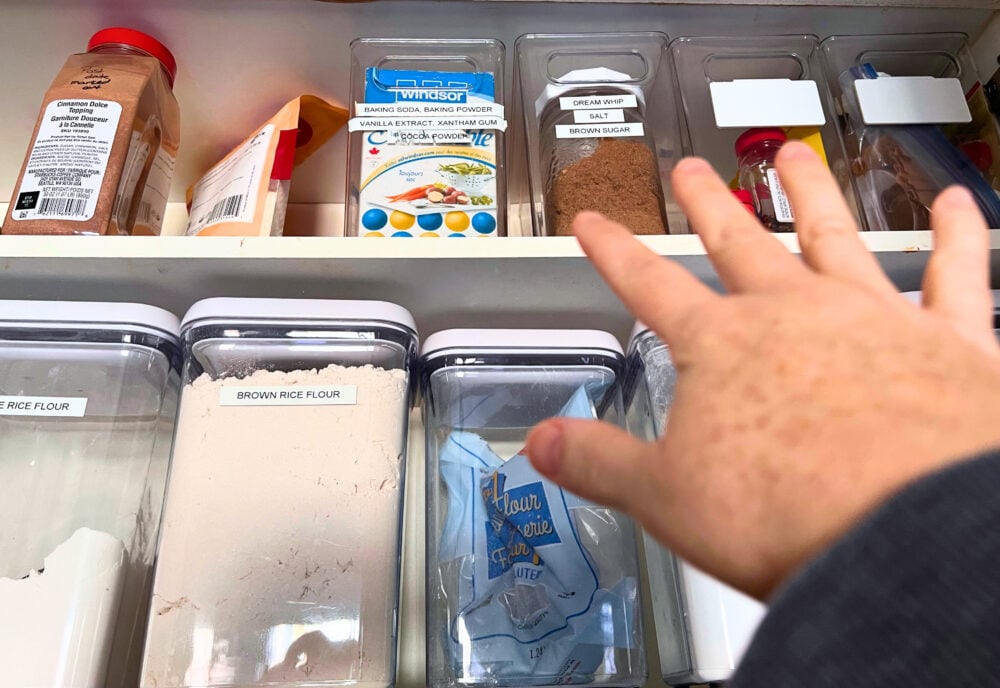 hand reaching up to top kitchen cabinet shelf of baking supplies